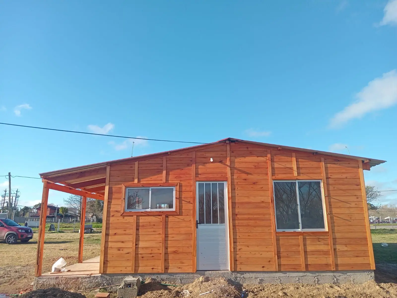 Vivienda de madera terminada, con galería al frente y aberturas de aluminio