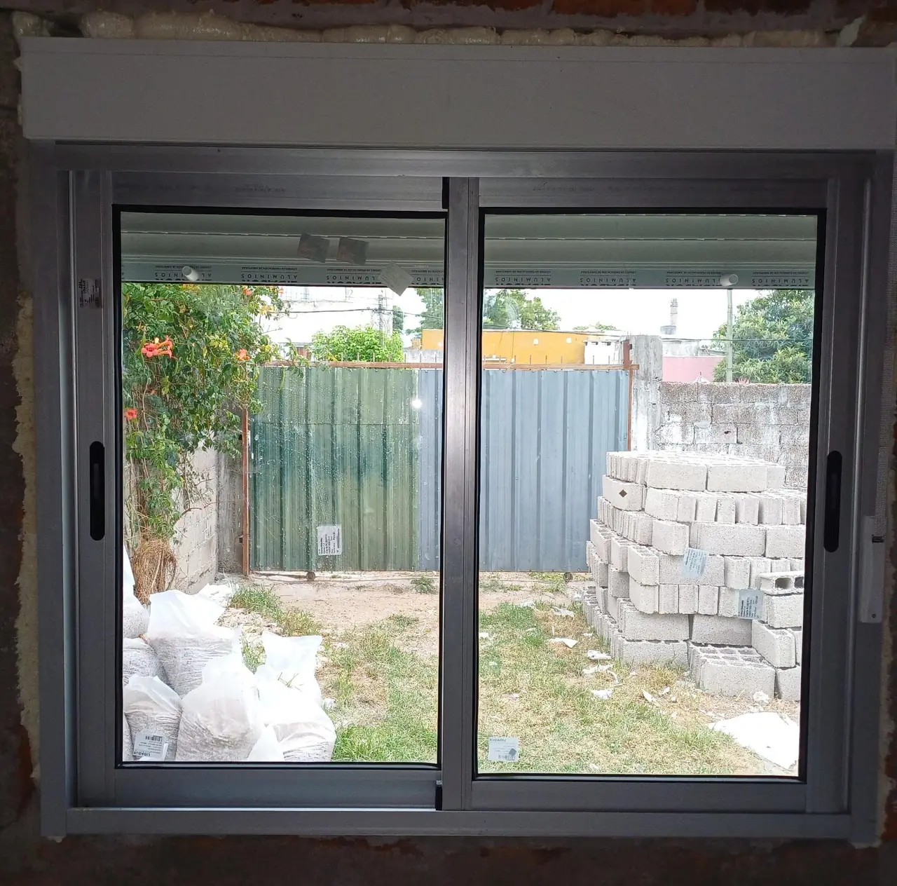 Ventana de aluminio con persiana en una obra de ladrillo