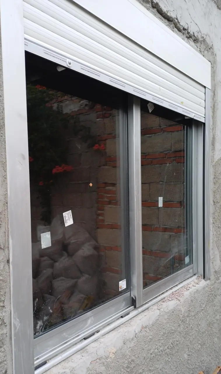 Ventana de aluminio con persiana vista desde el interior de una obra