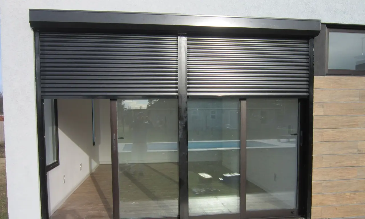 Cortina de enrollar de aluminio negra sobre una puerta ventana corrediza