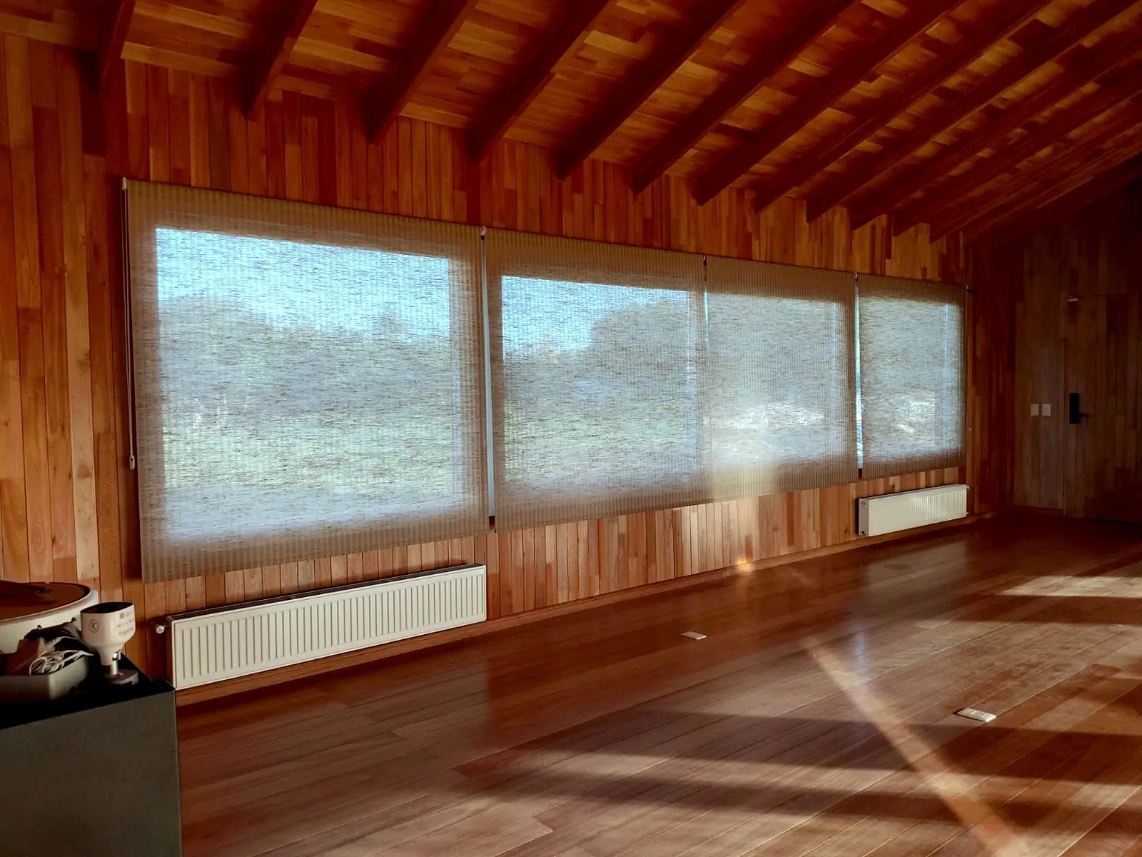 Galería con techo de madera y cortinas roller screen en todo el ventanal