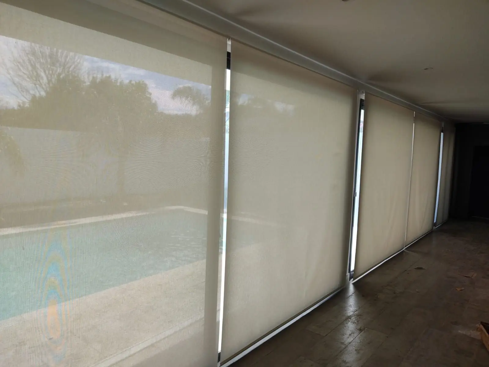 Cortinas roller claras en un ventanal con vista a la piscina