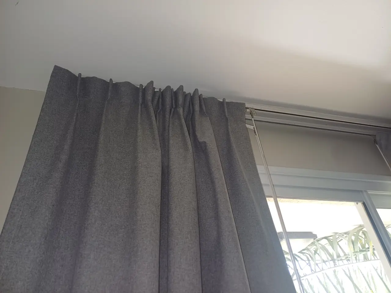 Detalle de los pliegues de una cortina tradicional blackout colgada del riel
