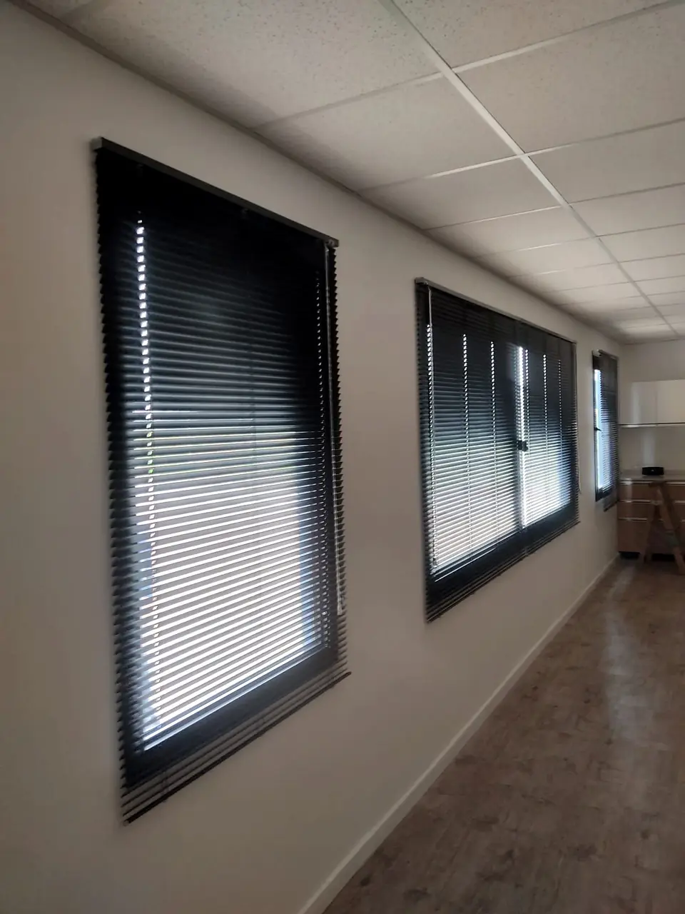 Venecianas negras en dos ventanas de un pasillo de oficina